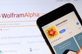 Mobile phone with WolframAlpha icon on screen close up with website on laptop. Blurred background with Wolfram Alpha logo