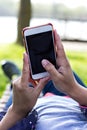 Mobile phone in woman's hand in a deckchair against the background of green grass. Time to rest. Royalty Free Stock Photo