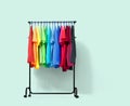 Mobile rack with color clothes on light green background. File contains a path to isolation. Royalty Free Stock Photo