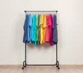 Mobile rack, with colorful T-shirts on the background of the wall