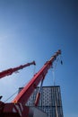 mobile red crane with risen boom. Truck cranes with big telescopic boom and hook suspension above blue sky Royalty Free Stock Photo