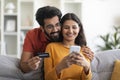 Mobile Shopping. Happy Indian Couple Using Smartphone And Credit Card At Home Royalty Free Stock Photo