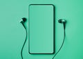 Mobile smart phone with headphones on a mint background with copy space empty screen