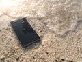 Mobile smart phone on the sandy beach with soft waves of sea background.  Internet of things concept Royalty Free Stock Photo