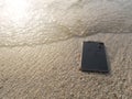 Mobile smart phone on the sandy beach with soft waves of sea background. Internet of things concept. Royalty Free Stock Photo