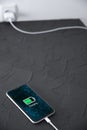 Mobile smart phone on wireless charging device on dark background. Icon battery and charging progress lighting on screen.