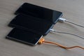 Mobile smart phones charging on wooden table