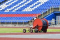 Mobile sprinkler on an empty green soccer field. Big drum with a hose for watering a football field Royalty Free Stock Photo