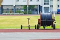 Mobile sprinkler on an empty green soccer field. Big drum with a hose for watering a football field Royalty Free Stock Photo