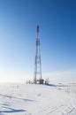 Mobile tower in a snow-covered white field against a blue sky Royalty Free Stock Photo