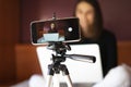 Mobile on a tripod recording a female vlogger at home