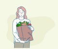 Young woman holding paper shopping bag full of fresh vegetables and smiling. Sustainable lifestyle concept. Royalty Free Stock Photo