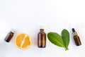 Mock up aromatherapy flatlay with orange essential oil bottles, citrus and leaves on white background.