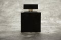 Mock up of a black bottle of men`s perfume on a brick gray wall background. Place for text.