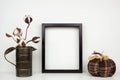 Mock up black frame with autumn cotton branch and plaid pumpkin decor on a shelf or desk