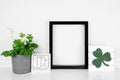 Mock up black frame with St Patricks Day decor on a white shelf against a white wall Royalty Free Stock Photo