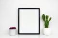 Mock up black frame wiMock up black frame with succulent and cactus plants on a white shelf or desk against a white wall Royalty Free Stock Photo