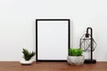 Mock up black frame against white wall with succulent plants and lamp on a wood shelf Royalty Free Stock Photo