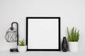 Mock up black square frame with home decor and potted plants with white shelf and wall