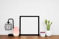 Mock up black square frame with home decor and potted plants on a wood shelf against a white wall Royalty Free Stock Photo