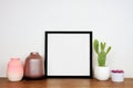 Mock up black frame with home decor and potted plants on a wood shelf with white wall Royalty Free Stock Photo