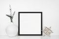 Mock up black square frame with modern home decor on a white shelf against a white wall Royalty Free Stock Photo