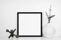 Mock up black square frame with modern home decor on a white shelf against a white wall Royalty Free Stock Photo