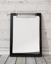 Mock up blank black clipboard on the white brick wall and the vintage wooden floor, background Royalty Free Stock Photo