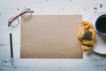 Mock-up blank craft sheet of empty paper, pen, eye glasses and morning coffee cup with croissant on white wooden desk Royalty Free Stock Photo