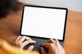 Mock up, a blank digital tablet on a white screen, Hand of woman  sitting typing on the keyboard at a brown wooden table at home Royalty Free Stock Photo