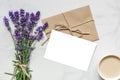 Mock up blank greeting card and envelope with lavender flowers and cup of cappuccino with copy space. top view