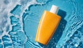 Mock-up of orange cream bottle with sunscreen cream on blue water surface with splashes and drops Royalty Free Stock Photo