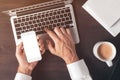 Mock up blank screen of modern smart phone in male hands over laptop computer Royalty Free Stock Photo