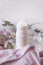 Mock up bottle of deodorant on a background of eucalyptus foliage. Soft focus. Light background