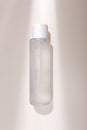 Mock up bottle of essence toner with no label in trendy natural light. Face skin care cosmetics, moisturizer, copy space