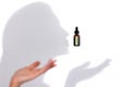 Mock up of brown glass serum or oil bottle with pipette and green stiker and shadows like silhouette of female profile and her