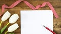Mock up clean sheet of paper with red pen, white and red quadrille ribbon and white tulips on old wooden rustic Background. Happy