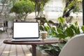 Computer laptop with blank screen and coffee cup on round table at outdoor cafe. Royalty Free Stock Photo