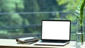 Computer laptop, books and houseplant on wooden table near window. Royalty Free Stock Photo