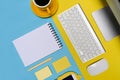 Computer, notepad, coffee cup and mobile phone on blue and yellow background. Royalty Free Stock Photo