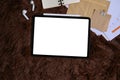 Digital tablet with blank screen, notebook, wireless earphone over brown fur rug. Royalty Free Stock Photo
