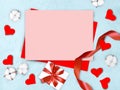 Mock up empty pink paper blank with cotton flowers, red hearts, gift box and ribbon on blue textured  background. Royalty Free Stock Photo