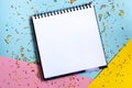 Mock up of empty spiral scketchbook with white paper on bright vibrant background with colorful confetti . Copy space. Royalty Free Stock Photo