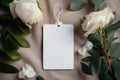 A mock-up of an empty tag on a rope lies with roses on a table on a cloth