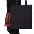 Mock-up. Girl in orange skirt holds black cotton tote bag. Handmade eco shopping bag for girls. Halloween mockups