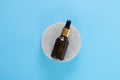 Mock up glass dropper bottle on a concrete stone gray podium, on a light blue background. Minimalism. View to the srerhu