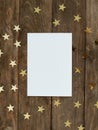 Mock up greeting card on wood rustic background with Christmas gold stars confetti. Invitation, paper. Place for text flat lay