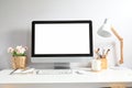 Mock up image of computer pc with white screen, coffee cup, plant, lamp and office supplies on desk Royalty Free Stock Photo