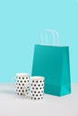 Mock up image with trending tea mugs near paper bag stand on blue background. Gift concept image with space for design. Gift shop Royalty Free Stock Photo