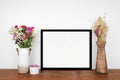 Mock up landscape black frame with plant and vases of cut flowers on a wood shelf Royalty Free Stock Photo